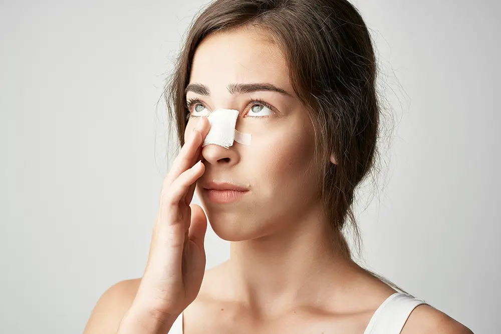 A woman with a bandage on her nose