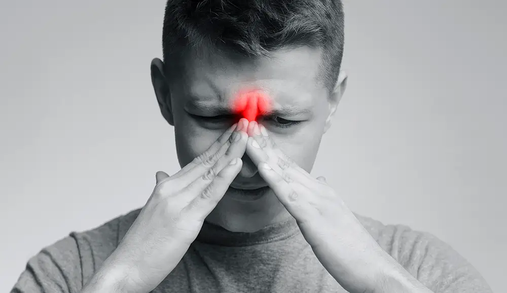 A young man suffering from sinus pressure, illustrating sinusitis