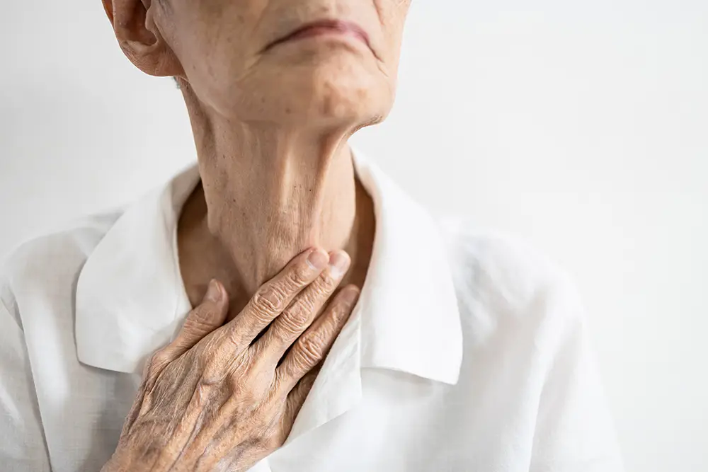 An elderly woman touching her throat