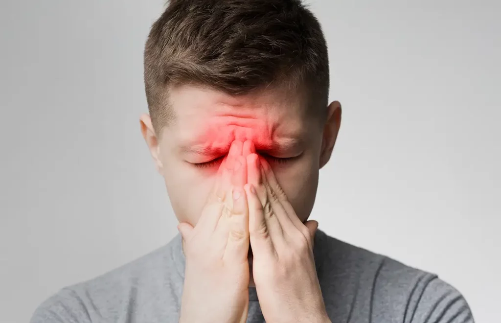 A man holding his hands over his face due to sinus pain
